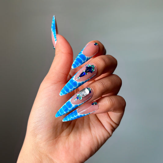 Blue Venom XL stiletto press-on nails with bold blue snake pattern, French tips, and sparkling blue rhinestones – fierce glam nail design