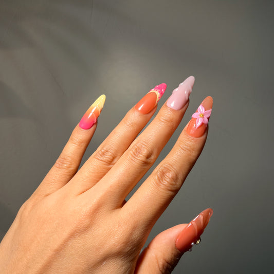 Pink floral press-on nails with glossy finish and delicate accents for an elegant, feminine look suitable for everyday wear or events.