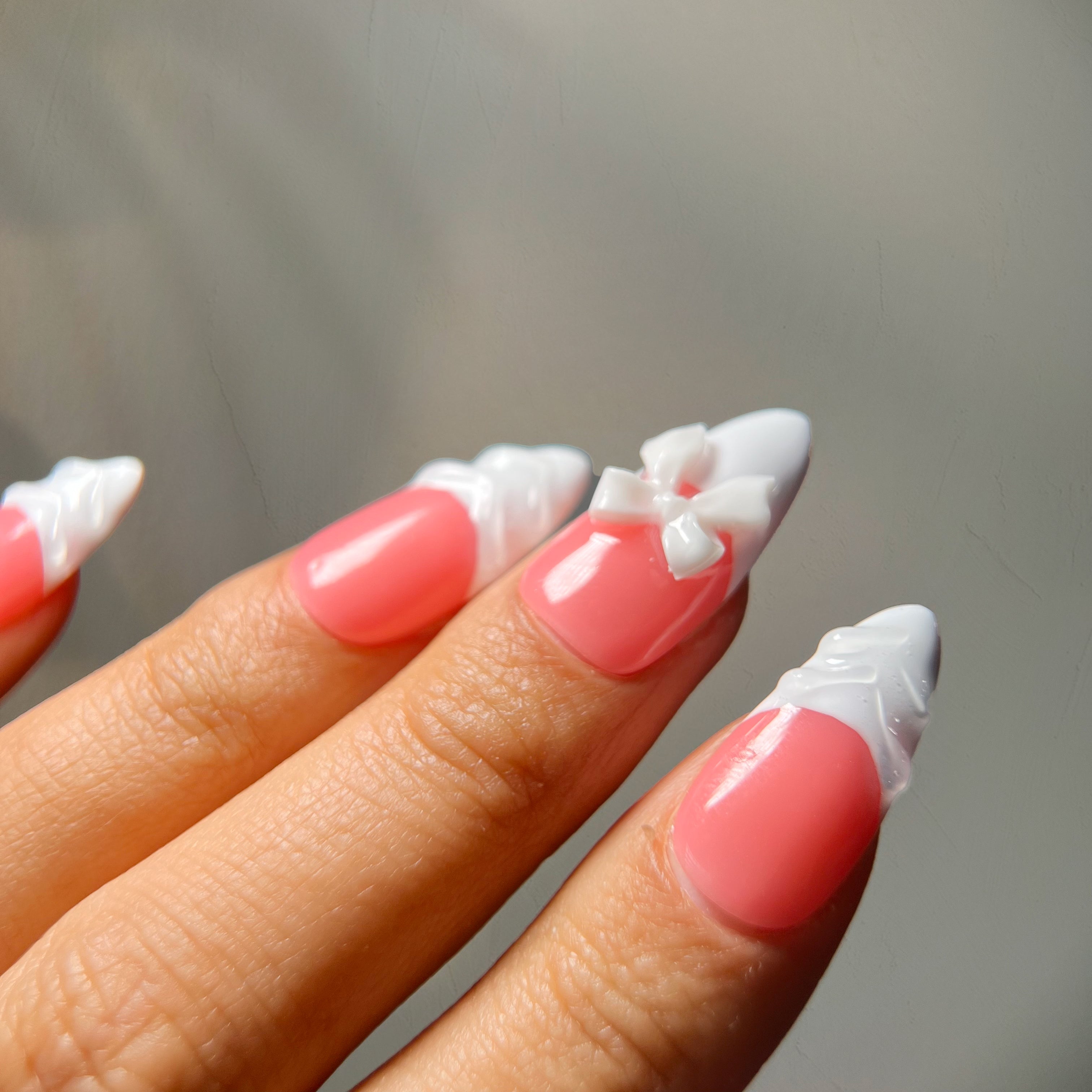 Medium almond French press-on nails with white textured tips and ribbon bow charms for an elegant, princess-inspired design.