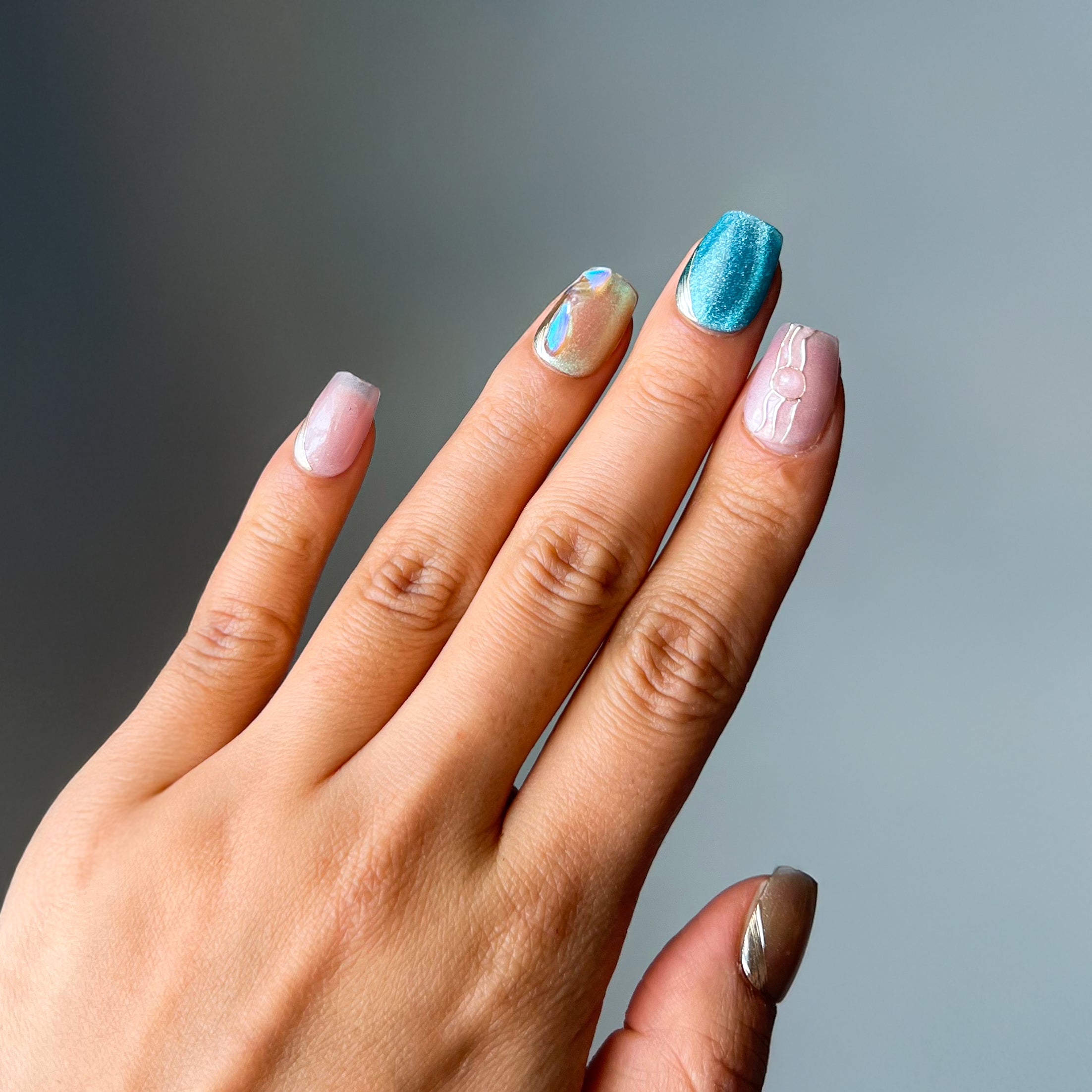 Tidal Glitz short squoval press-on nails with oceanic blue tones, rhinestone accents, and a glossy shimmering finish – elegant, bold nail design
